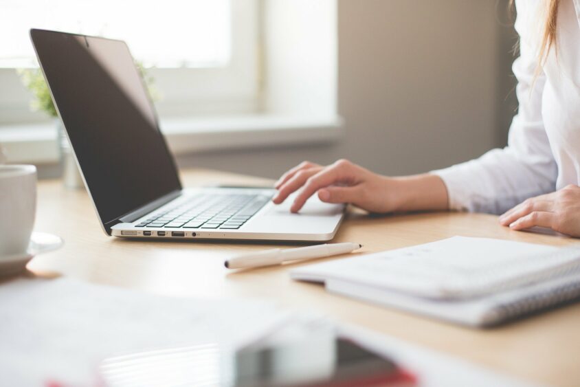 A person typing on a laptop at a desk.